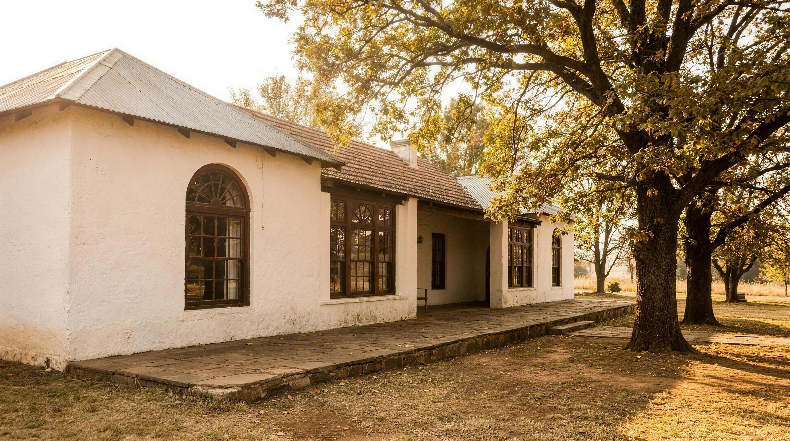 Whitewashed heritage farmhouse with timber sash windows under oak trees, Irene