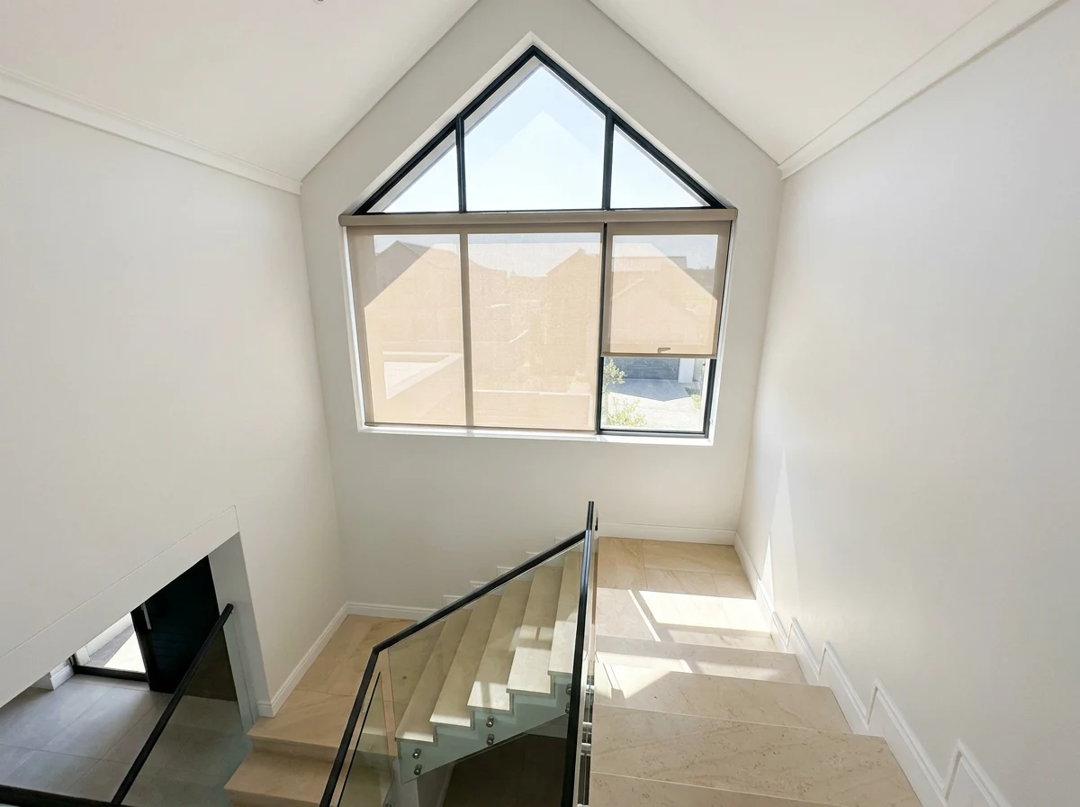 Motorised skylight blind fitted to a gable window above a double-volume stairwell, Southdowns Estate